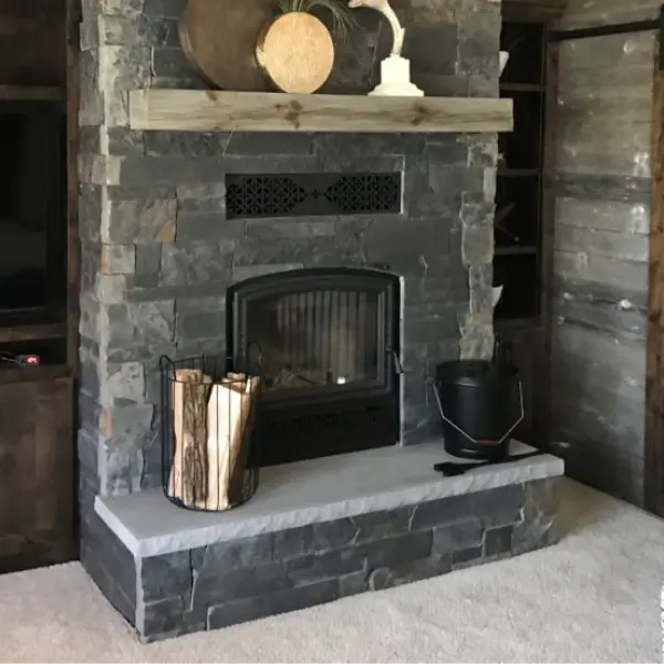 RSF Opel high-efficiency wood-burning fireplace installed with custom dark stone veneer surround and hearth.