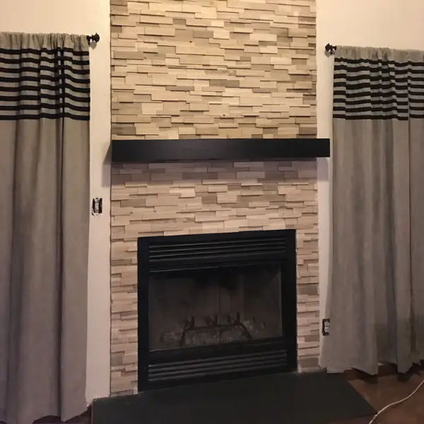 New wood burning prefab fireplace installed with stacked stone surround floating mantel and custom hearth
